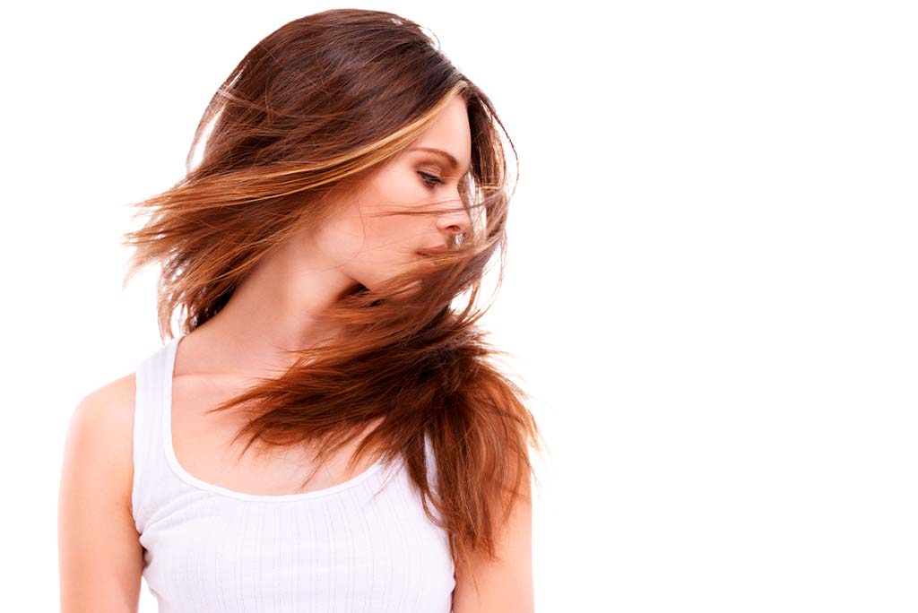 Jovem mulher com os cabelos cheios e volumosos em movimento.